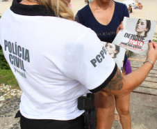 Policial civil entregando panfleto da campanha contra a dengue para veranista