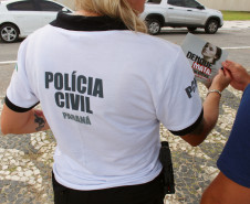 Polcial civil de costas entregando panfleto da campanha contra a dengue para um homem