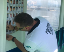 Policial da PCPR colocando cartaz de crianças desaparecidas