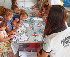 Policial civil orienta diversas crianças a colorir desenhos