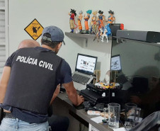 Policiais civis analisam notebook no interior de um quarto