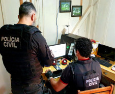 Policiais civis analisam computador no interior de um quarto