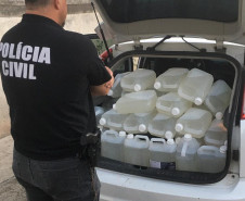 Policial observa garrafas com produto adulterado