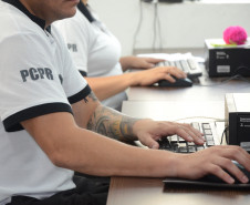 Dois policiais civis sentados, ao computador