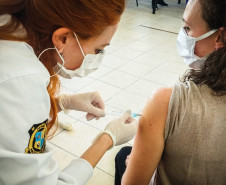 Policial aplicando vacina no braço de uma mulher