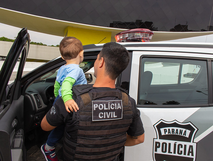 Policial segura criança no colo.