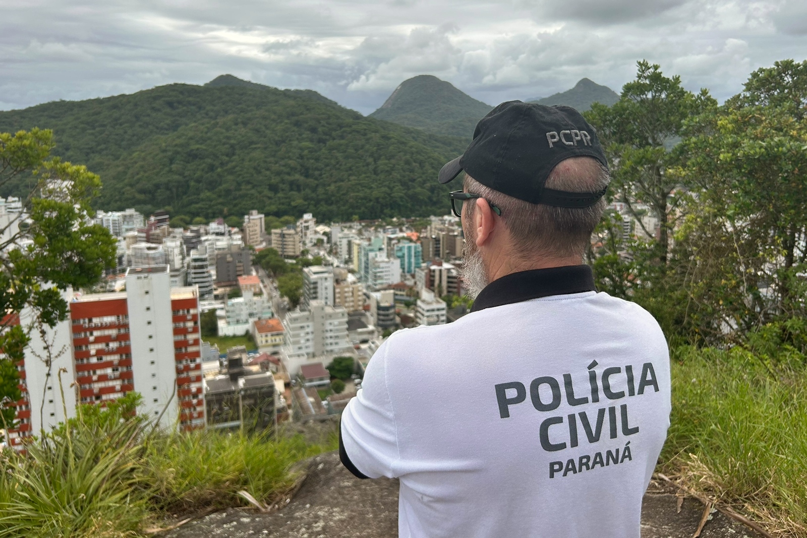 Policial civil observa cidade do alto de um morro