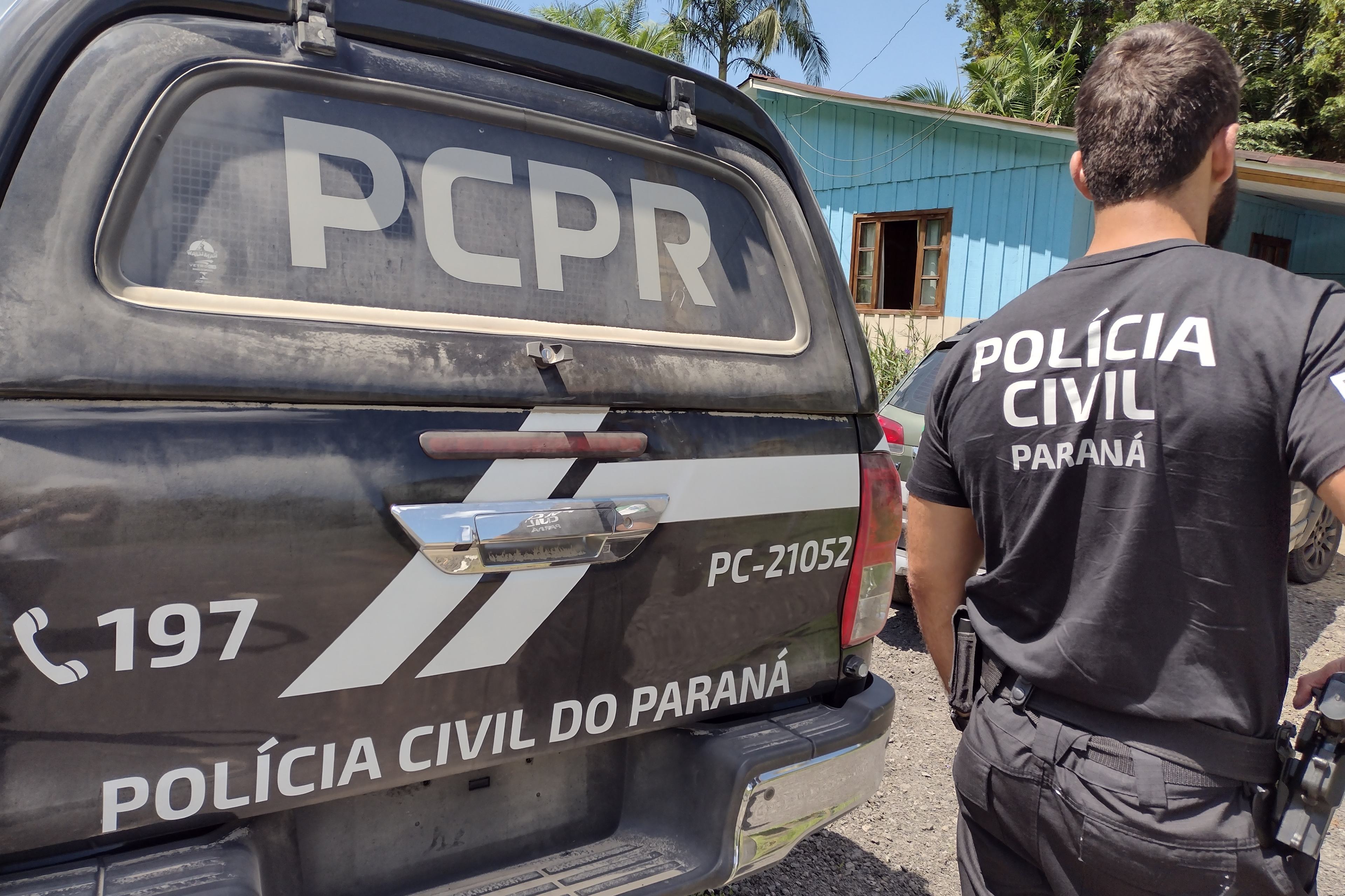 Policial civil ao lado de viatura