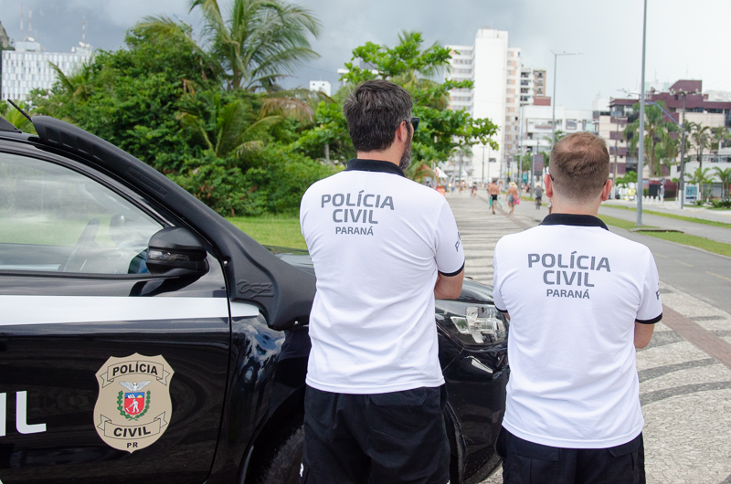 Dois policiais ao lado de viatura no litoral