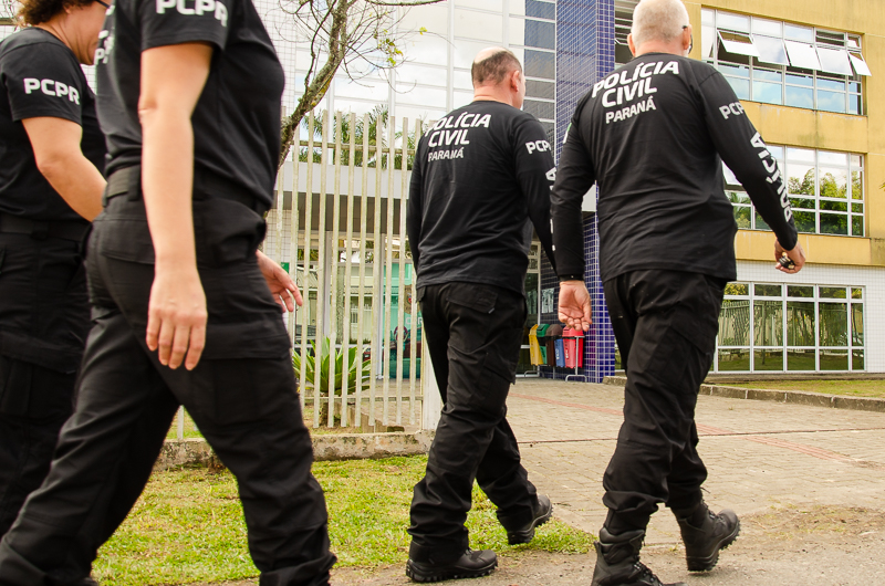 Vários policiais civis entrando em viatura