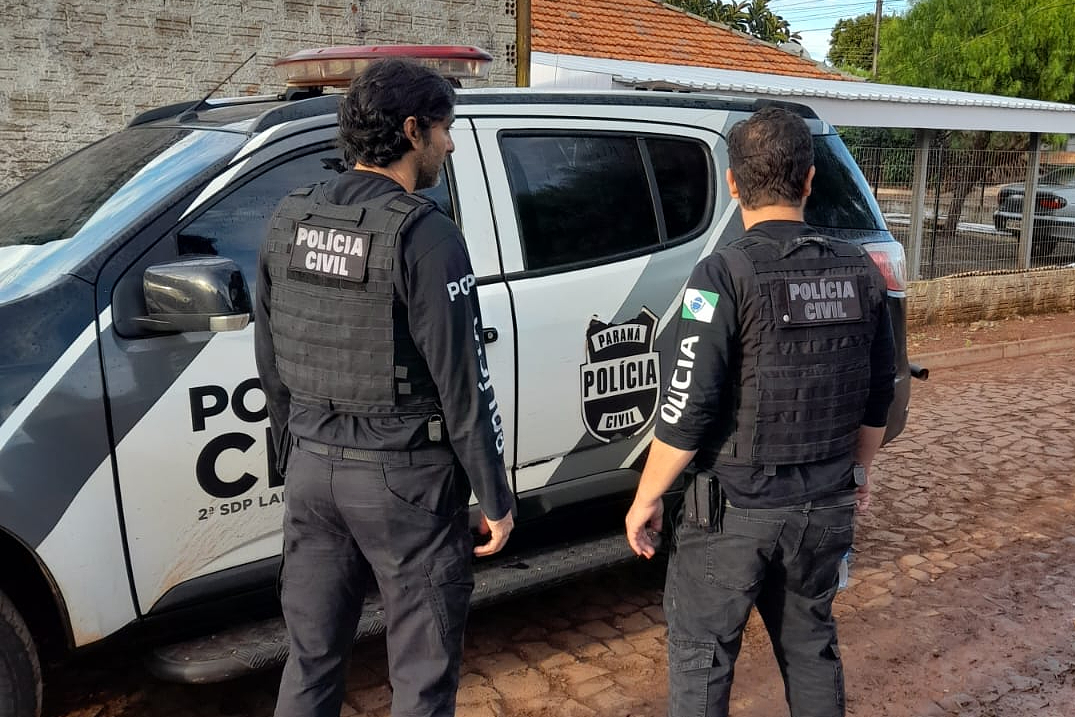 Dois policiais civis ao lado de viatura