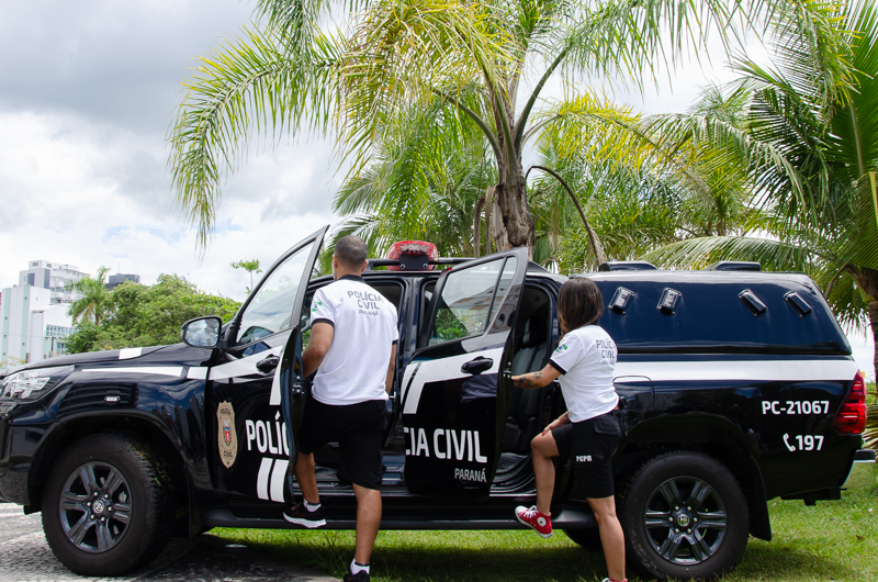 Dois policiais civis entrando em viatura