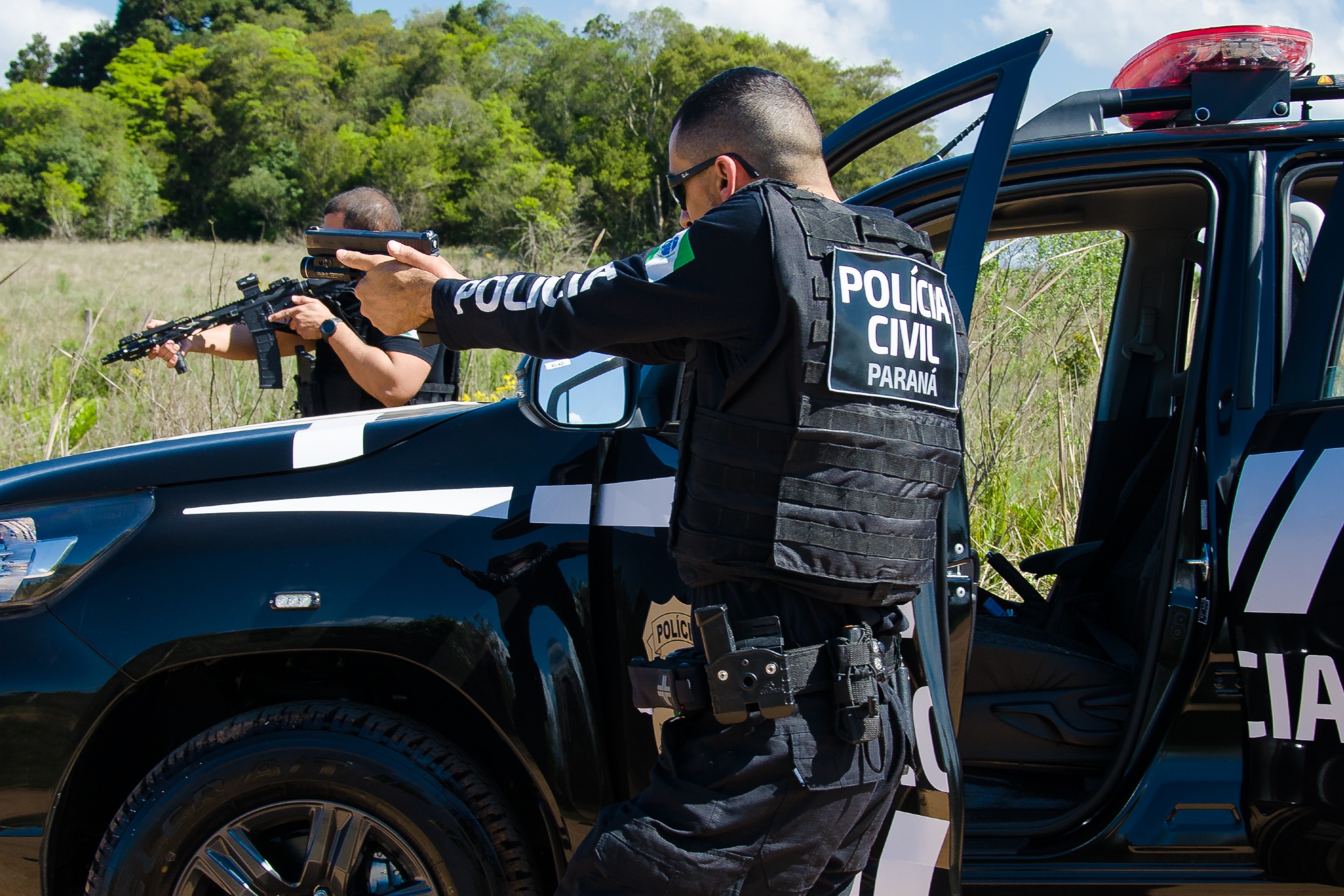 Dois policiais civis apontando arma em abordagem