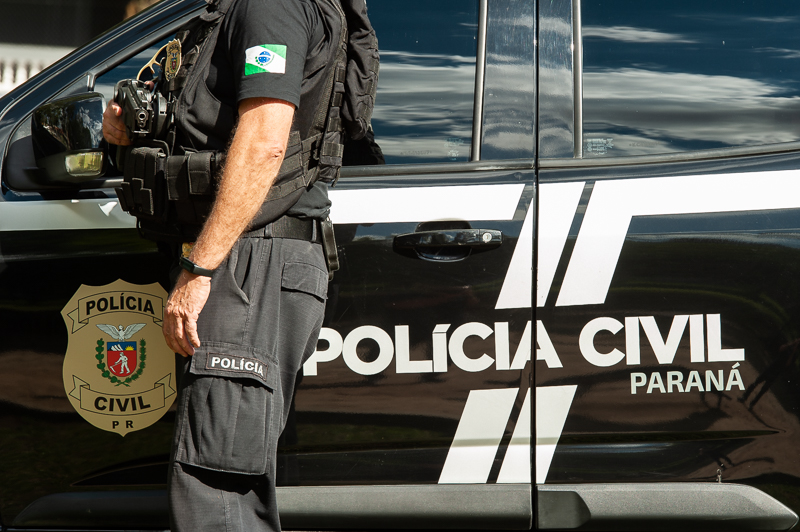 Policial civil ao lado de viatura