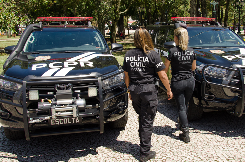 Duas policiais civis entre viaturas