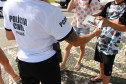 Policial civil entregando panfleto da campanha contra a dengue no calçadão do Litoral