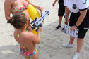 Policial civil distribuindo material preventivo na areia da praia para população