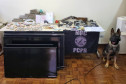 Cão farejador junto a drogas, armas, dinheiro e produtos apreendidos