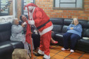 Papai Noel cumprimentando idosas no sofá do lar