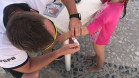 Policial da PCPR colocando pulseira de identificação em criança
