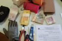 Carteiras, dinheiro, luva, alicate, estilete e chave de fenda sobre uma mesa