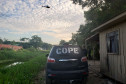 Policial civil ao lado de viatura do COPE e helicóptero sobrevoando o local