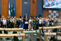 Delegado segurando o diploma junto aos participantes, posando para foto