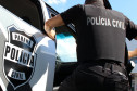 Policial civil entrando em viatura, com destaque para o brasão da Polícia Civil