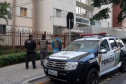Policiais civis na calçada, ao lado de viatura