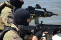 Dois policiais civis na proa do barco, apontando armas