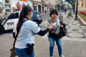 Policial civil entregando máscara para transeunte