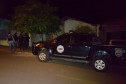Policiais entrando um uma residência. Ao lado, viatura estacionada.