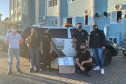 Policiais civis com caixa com máscaras, junto a viatura