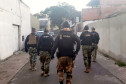 Vários policiais andando na rua, em frente ao local