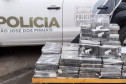 Tabletes de droga empilhados ao lado de uma viatura