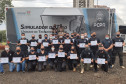 Participantes do curso reunidos para foto ao lado de simulador de tiro