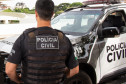 Policial civil ao lado de viatura