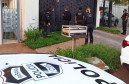 Policiais civis em frente a uma residência. Em primeiro plano, capô de viatura com brasão da polícia civil