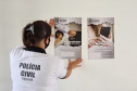 Policial civil fixando cartaz na parede