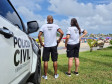 Dois policiais ao lado de viatura observam movimento no litoral
