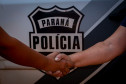 Policiais civis se cumprimentam em frente ao brasão da policia civil