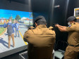 Dois policiais militares apontando as armas para tela de simulador da polícia civil