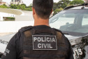Policial civil de costas, ao lado de viatura