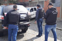 Três policiais civis ao lado de viatura