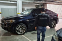Policial civil de costas observando veículo de luxo estacionado