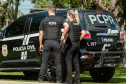 Dois policiais ao lado de viatura