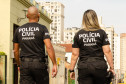 Dois policiais civis de costas, caminhando pela rua