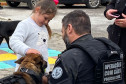 Policial civil acompanha criança acariciando cão policial