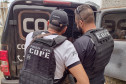 Dois policiais civis ao lado de viatura