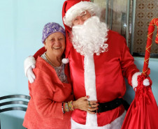 Senhora sorrindo abraçada no papai noel